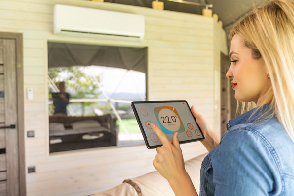 Femme tenant une table pour régler son thermostat dans le salon