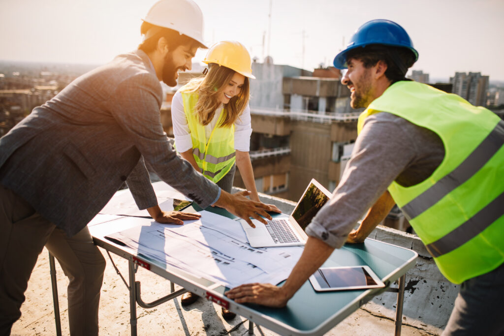 Constructeurs de maisons et artisans sur un chantier en train e discuter devant un ordinateur