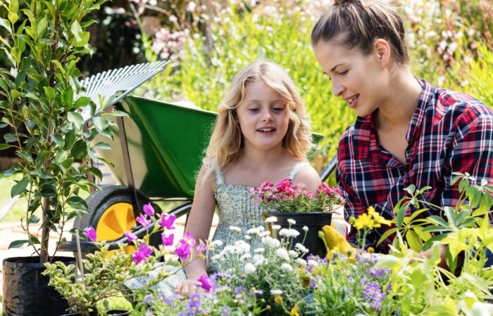 Femme et petite fille devant des fleurs dans un jardin, en plein explication