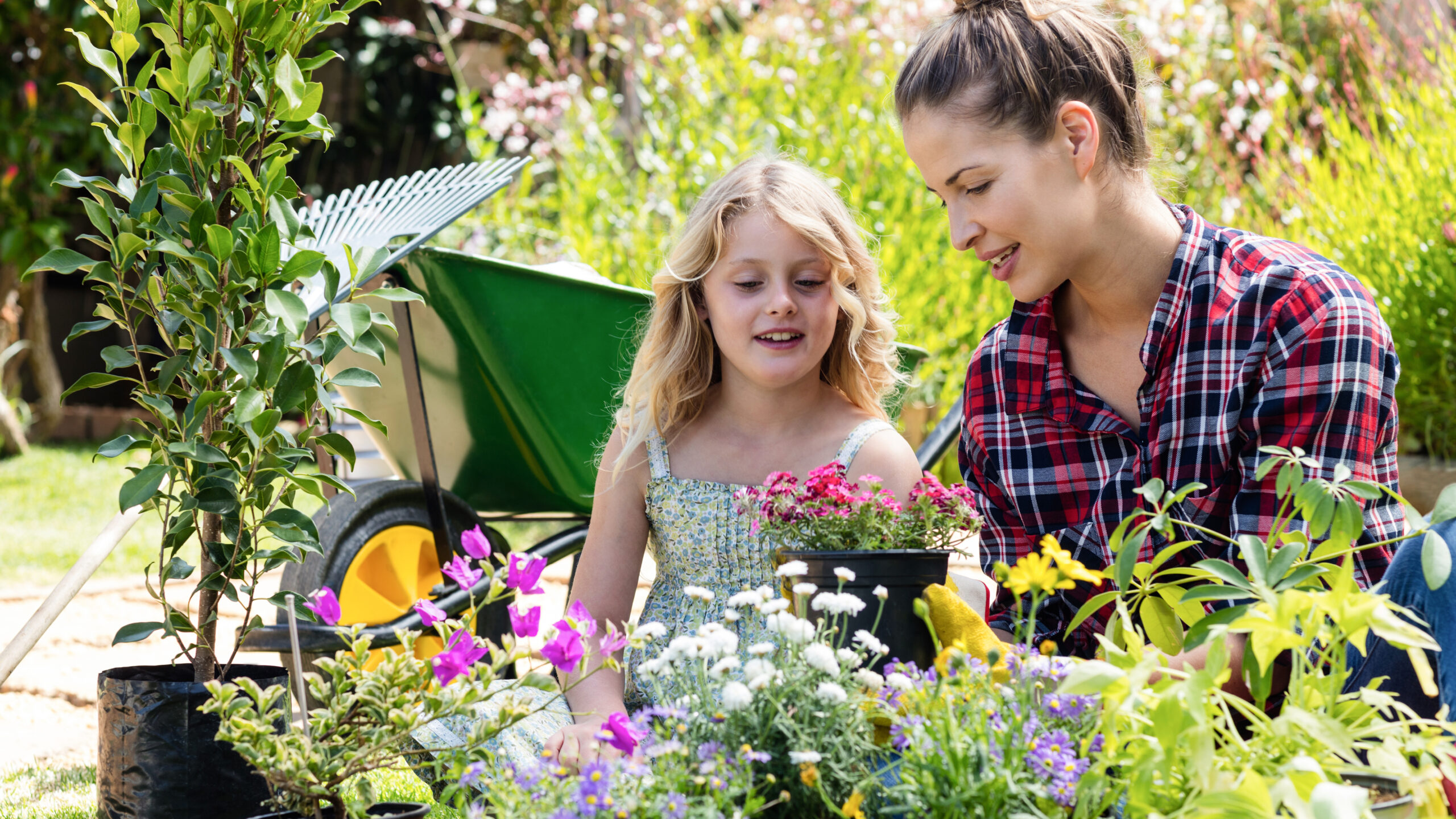 Femme et petite fille devant des fleurs dans un jardin, en plein explication