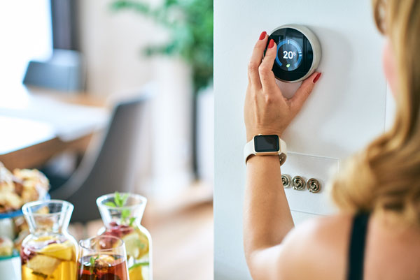 Femme réglant un thermostat connecté