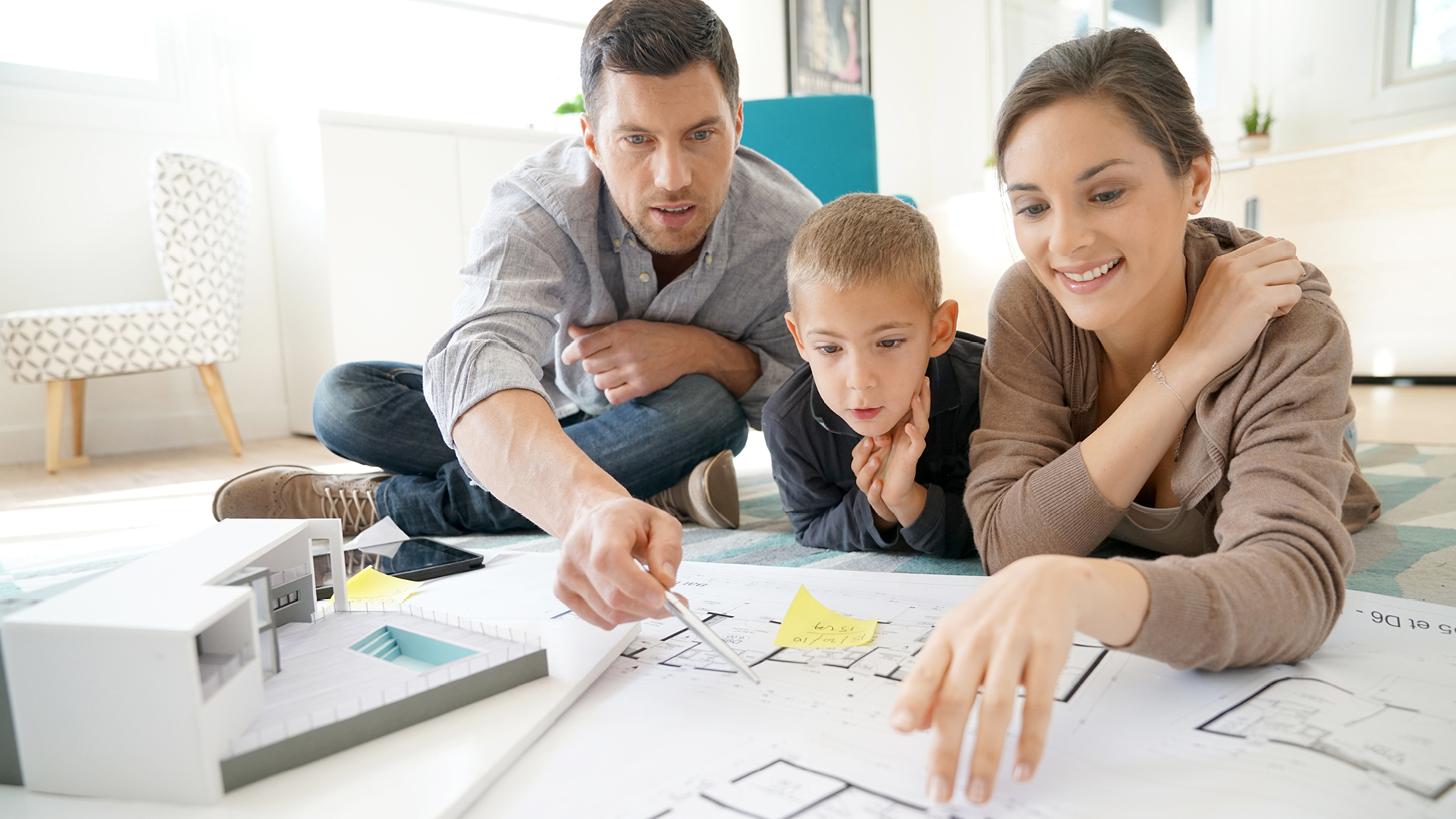 étapes pour faire construire sa maison, couple avec enfant devant un plan de maison