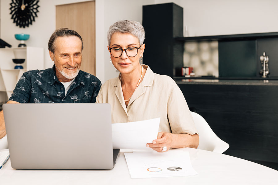 terrain constructible couple devant des papiers et ordinateur chez eux